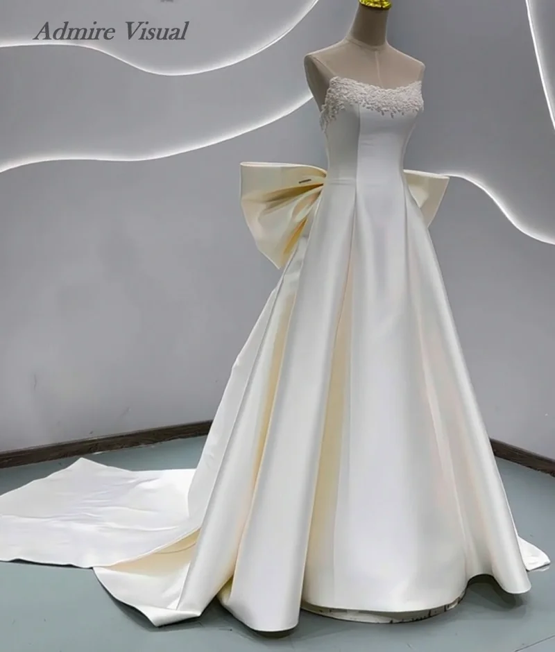 분리 가능한 큰 리본이 달린 A라인 새틴 민소매 비주얼 웨딩드레스를 감상하세요. 맞춤 제작 가능한 신부 가운