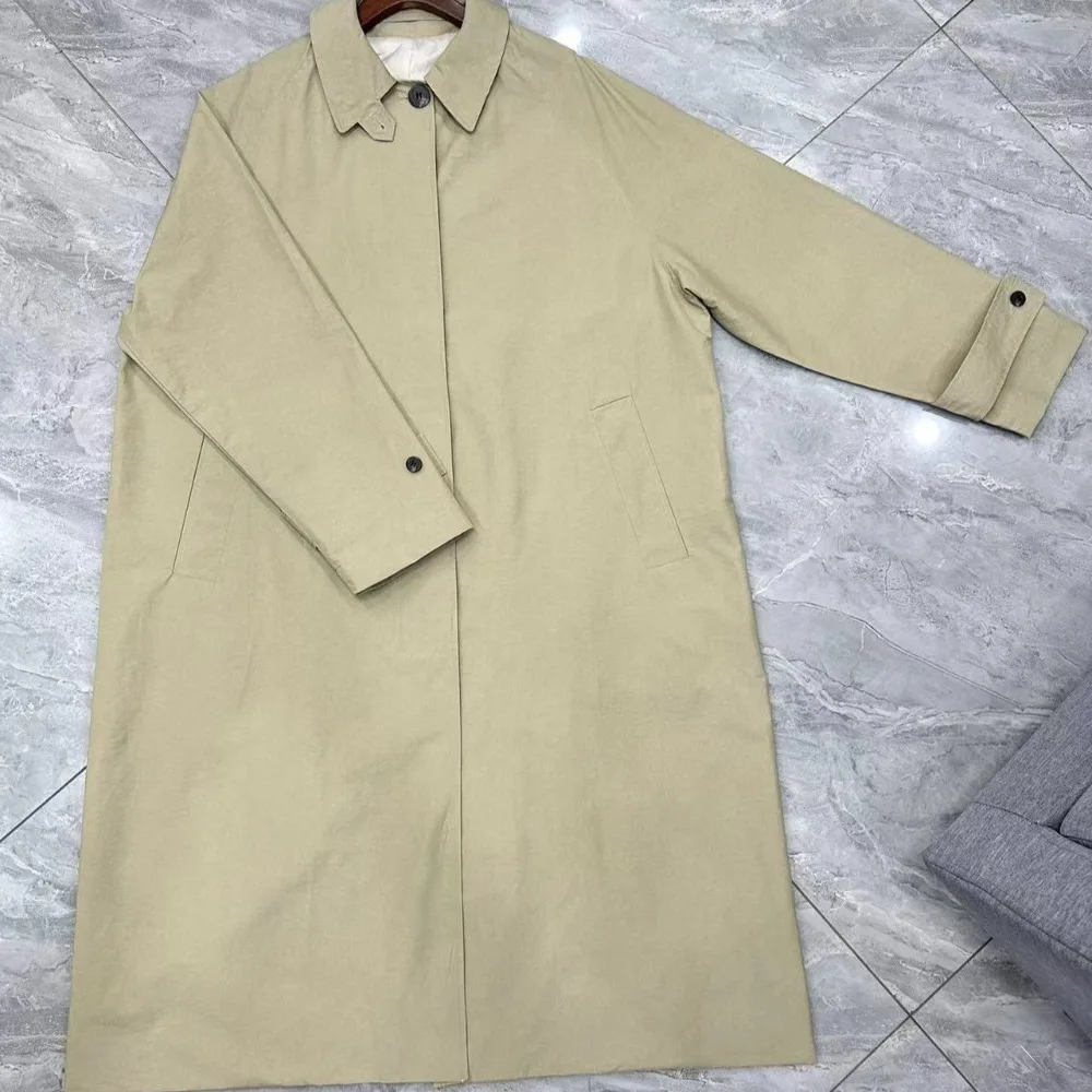 Jesienny płaszcz wiatrówka o klasycznym kroju, z wysokim rozcięciem, wykonany z mieszanki bawełny, o kroju litery A, średniej długości, zapinany na wiele guzików.