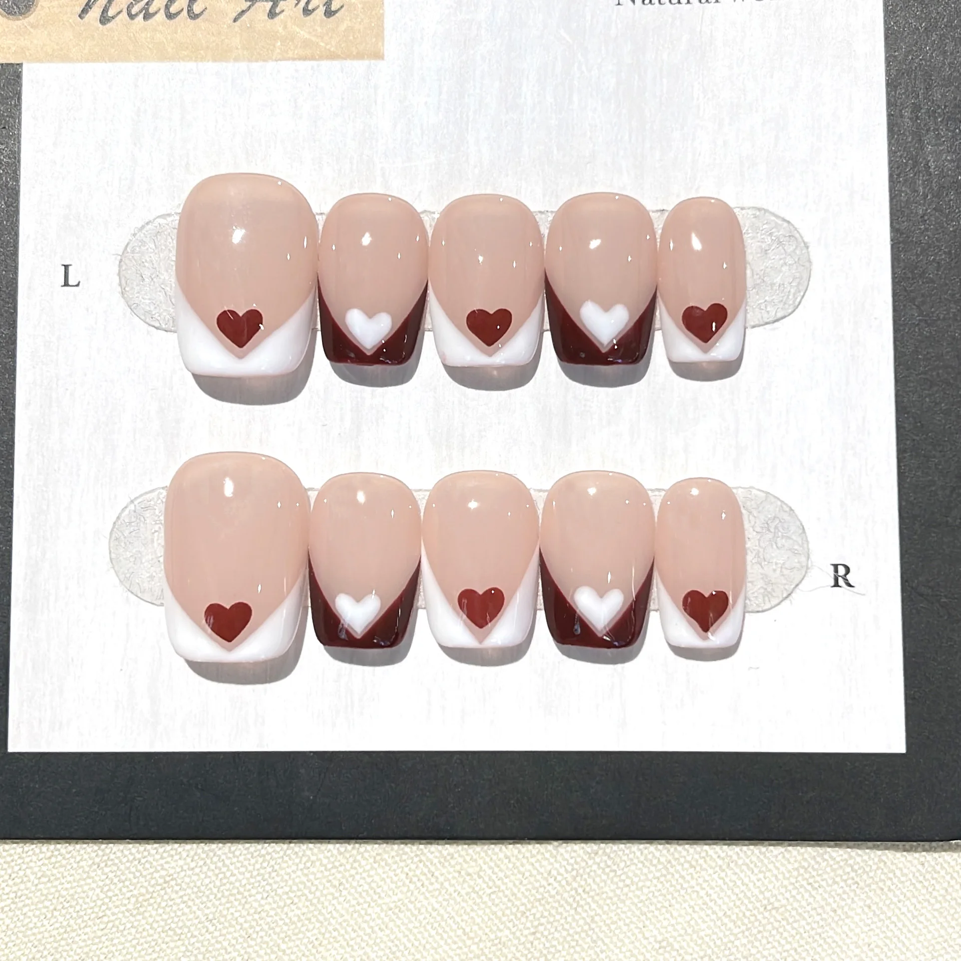 10 Stück originale, handgefertigte künstliche Nägel, kurze, quadratische, farblich neutral gehaltene French-Nägel zum Aufkleben mit roten und weißen Herz-Nagelspitzen.