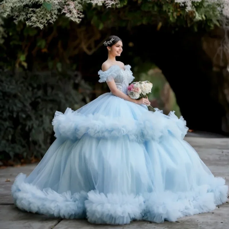 

Светло-голубое платье для квинсеаньеры с открытыми плечами, блестящими кристаллами, кружевными оборками и длинным шлейфом. Платье для 15-летия.