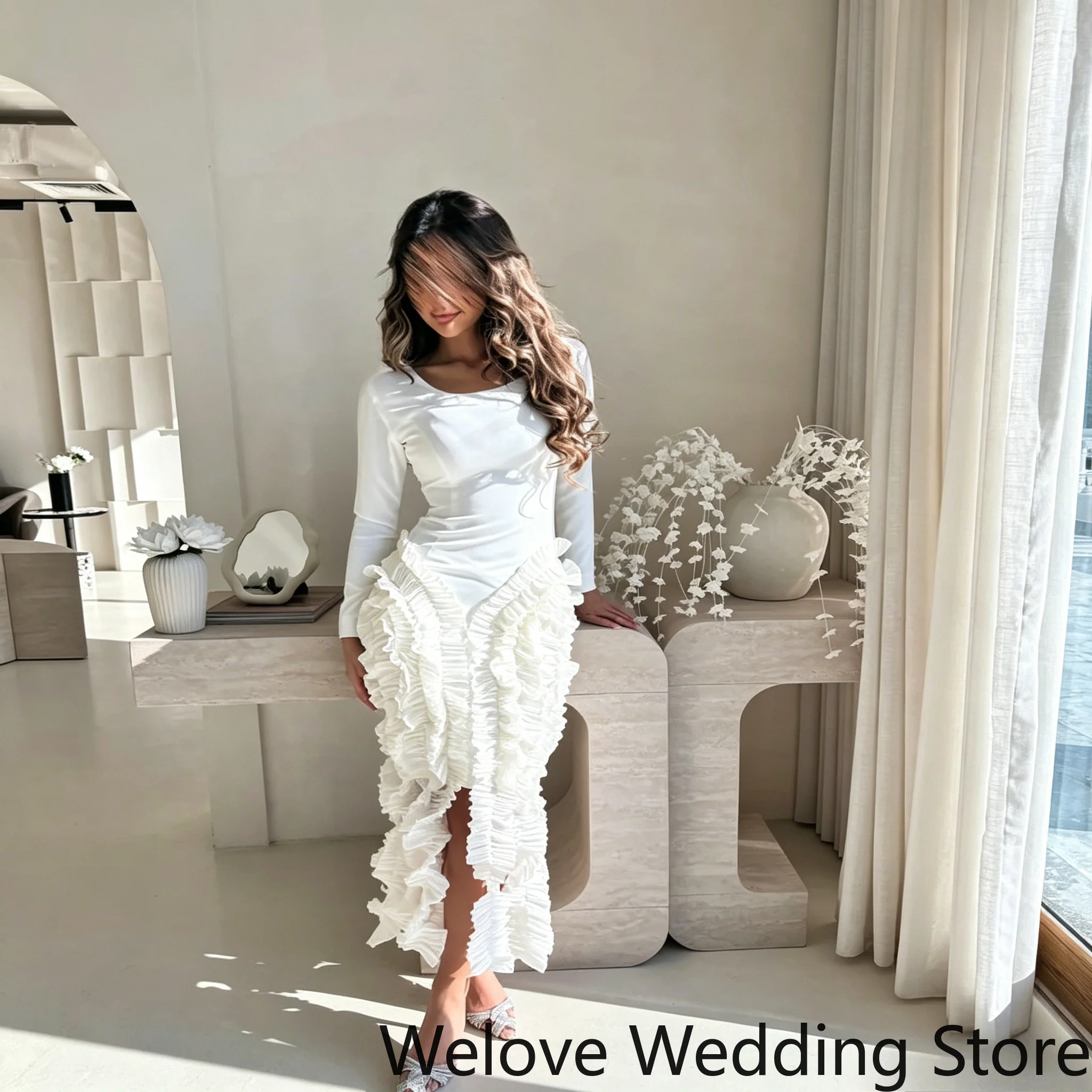 Elegante vestido midi formal blanco con un elegante cuerpo de manga larga y una impresionante falda asimétrica con volantes y abertura frontal.