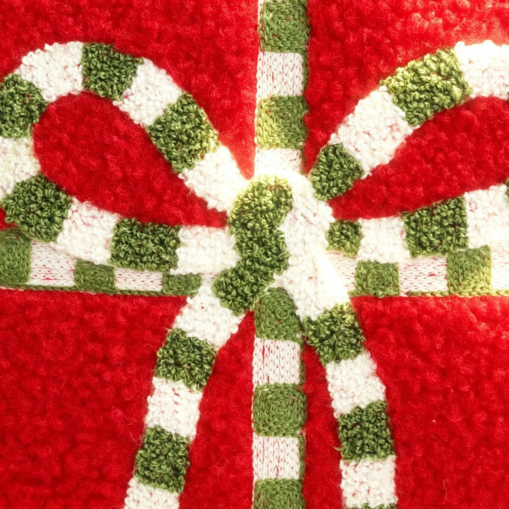 Close-up of embroidered green-and-white bow on red fabric