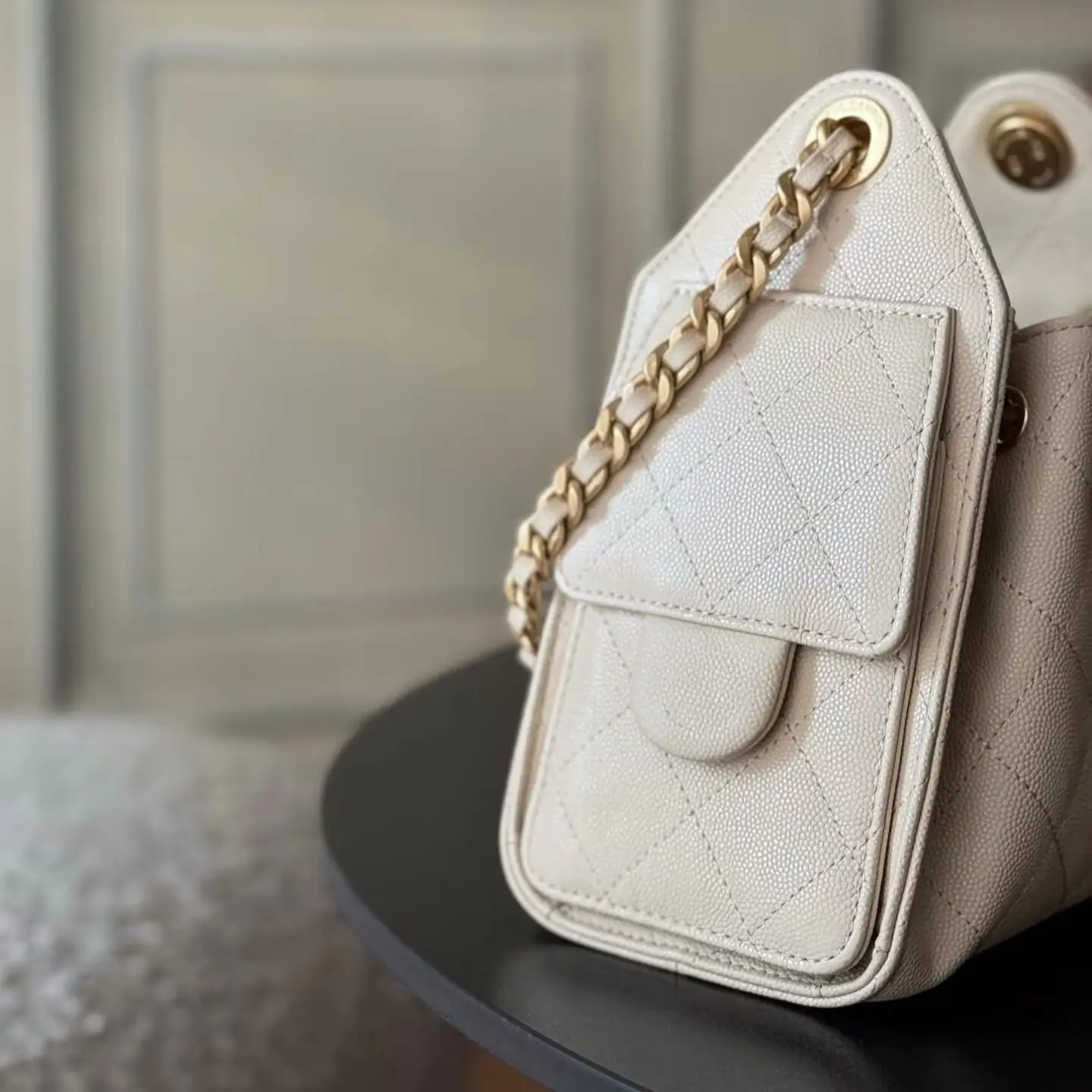 Cream-colored leather trapeze shoulder bag with diamond quilted texture and a detachable dual-use chain.
