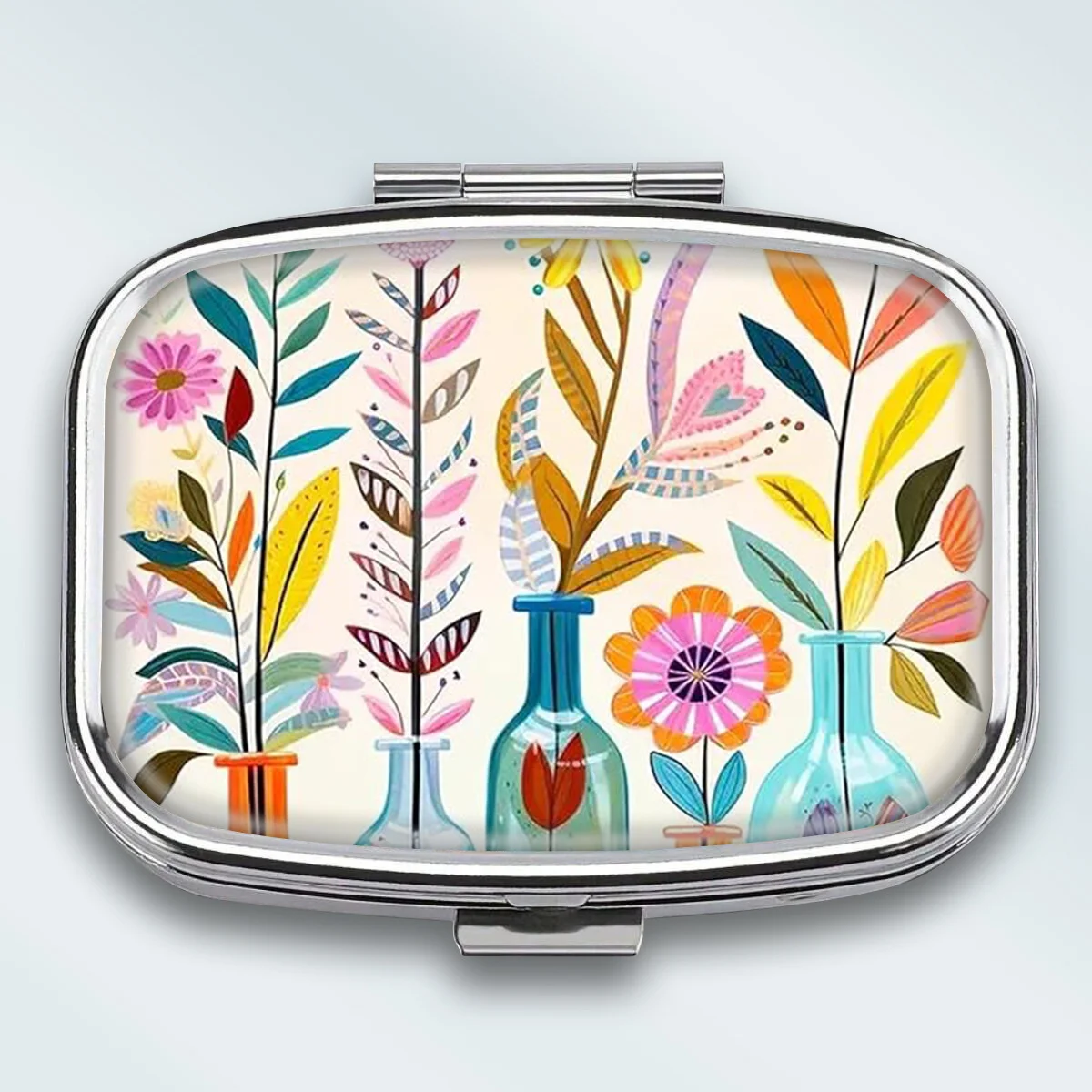 A Compact Metal Pill Box with Two Compartments, Decorated with Modern Floral Vase Illustrations, Is a Portable Decorative Vitamin Organizer, Making It a Unique Gift to Put in Your Pocket or Purse.