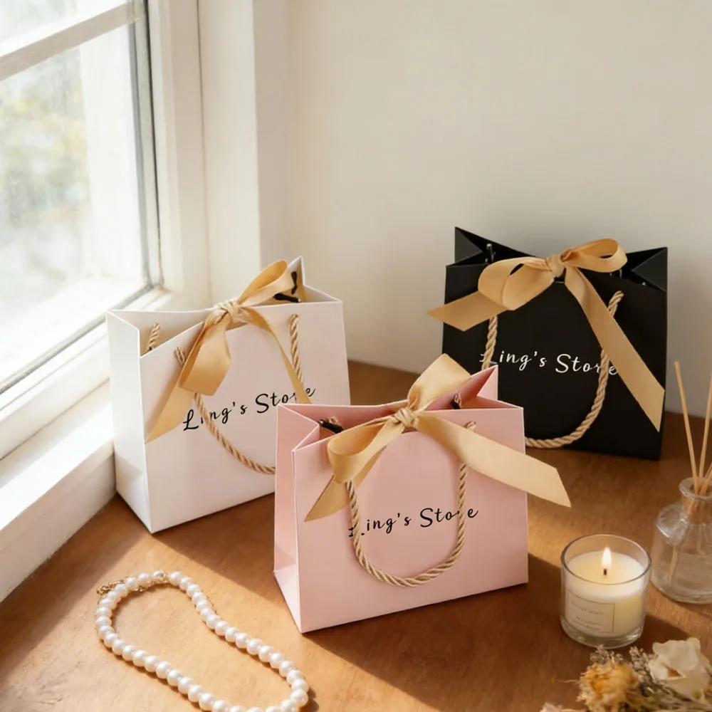 

50/100Pcs Custom Logo 14x6x12cm Jewelry Paper Handle Bag Bowknot Ribbon Wedding Gift Organizer Folder Handbag Cosmetic Packaging