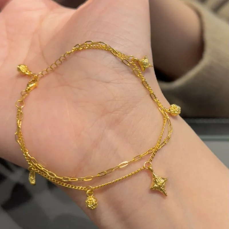 Bransoletka damska w stylu light luxury, złota, z gwiazdą czterokątną, niszowy design, wyrafinowany, podwójny łańcuszek, do noszenia warstwowo, ekskluzywna.