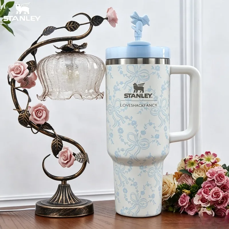 bouteille-d'eau-isotherme-stanley-quencher-h20-de-40-oz-couleur-creme-avec-mini-fleur-et-nœud-bleu-clair-en-acier-inoxydable-anti-fuite-construction-parfaite