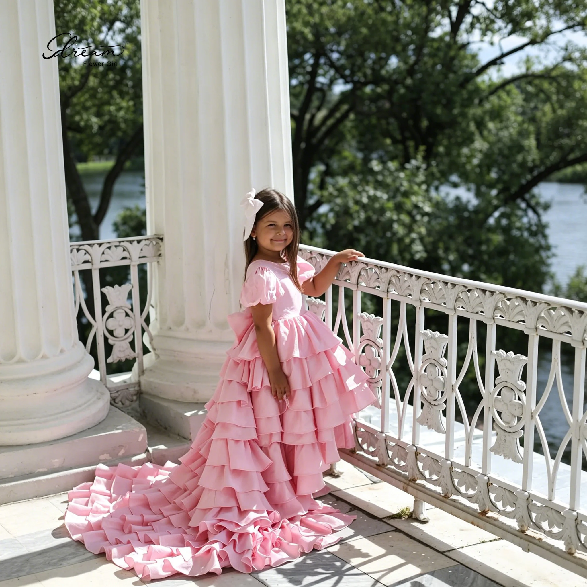 Formal Children's Gown Pink Floor Length Ball Gown featuring Puff Sleeves a Wide Lace Trimmed Skirt and a Bow Tie at the Back