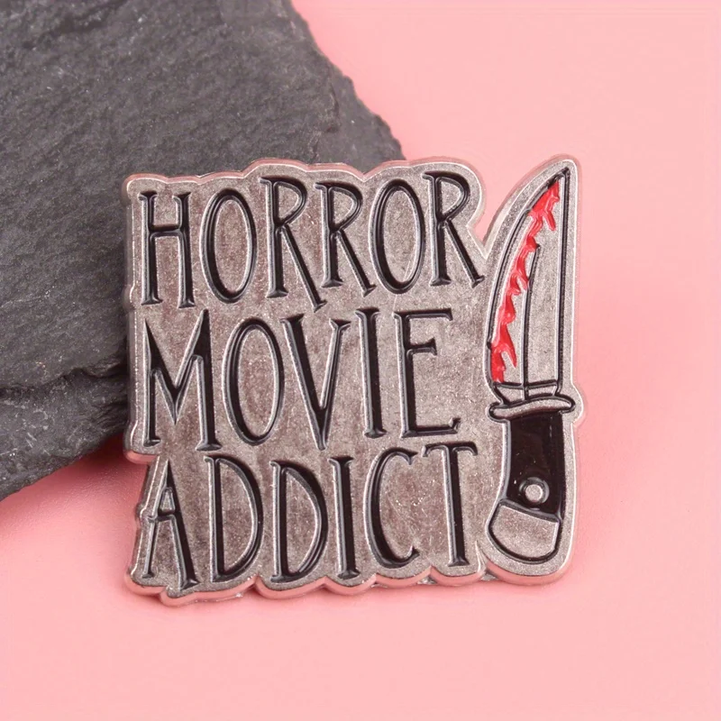 Slasher Cinema Emaille Pin – Distressed Metal Finish mit Blutspritzmesser-Motiv, „Horror Movie Addict“ Typografie für Gore F