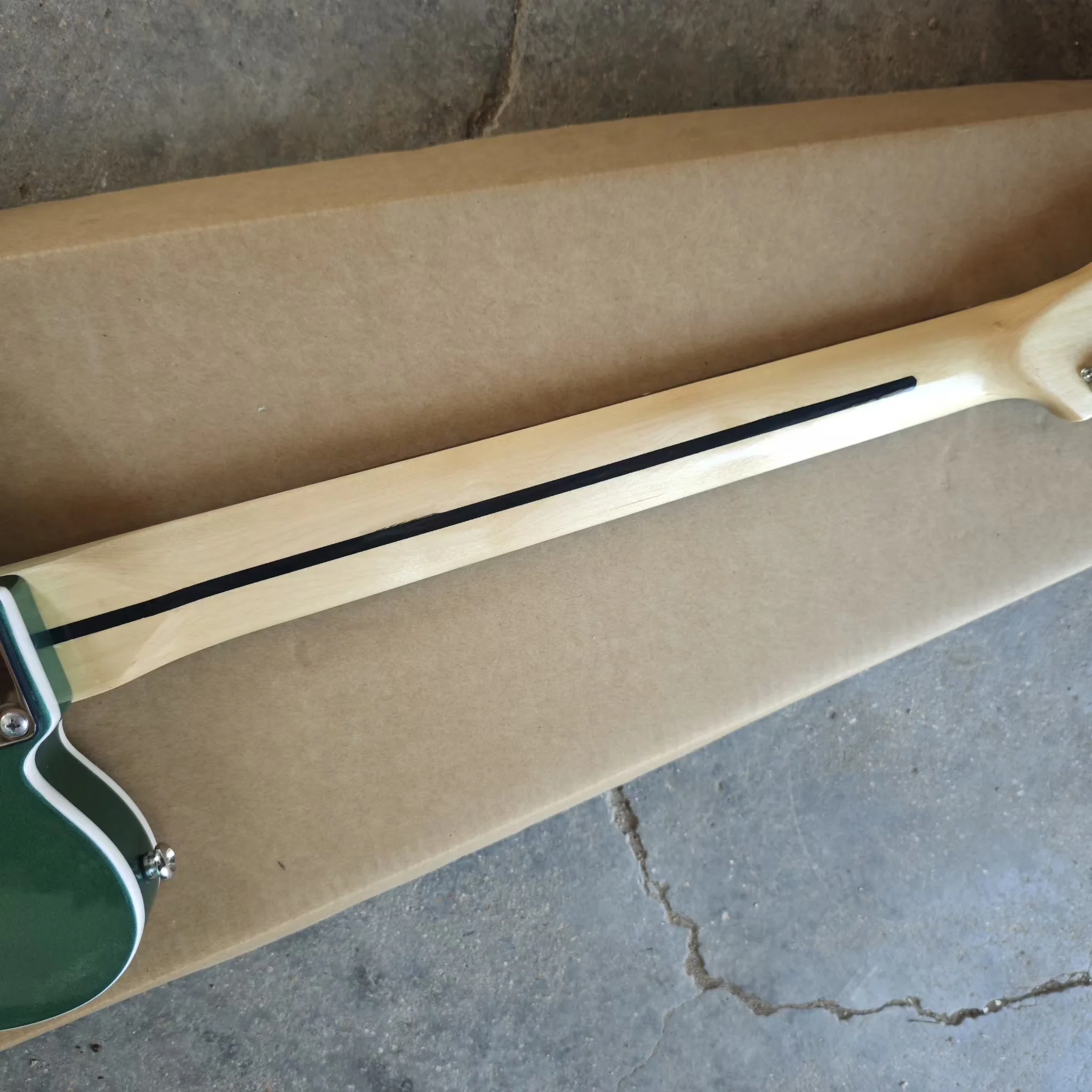 Six string electric guitar with white edging, green silver powder paint finish, black protective plate