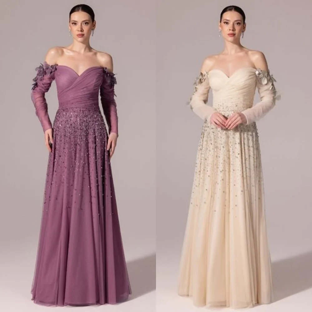 ชุดราตรีทรงเอไลน์แบบเปิดไหล่ ประดับด้วยผ้าทูลล์ระยิบระยับ แต่งดอกไม้ ลูกปัด และเลื่อม ดีไซน์หรูหรา