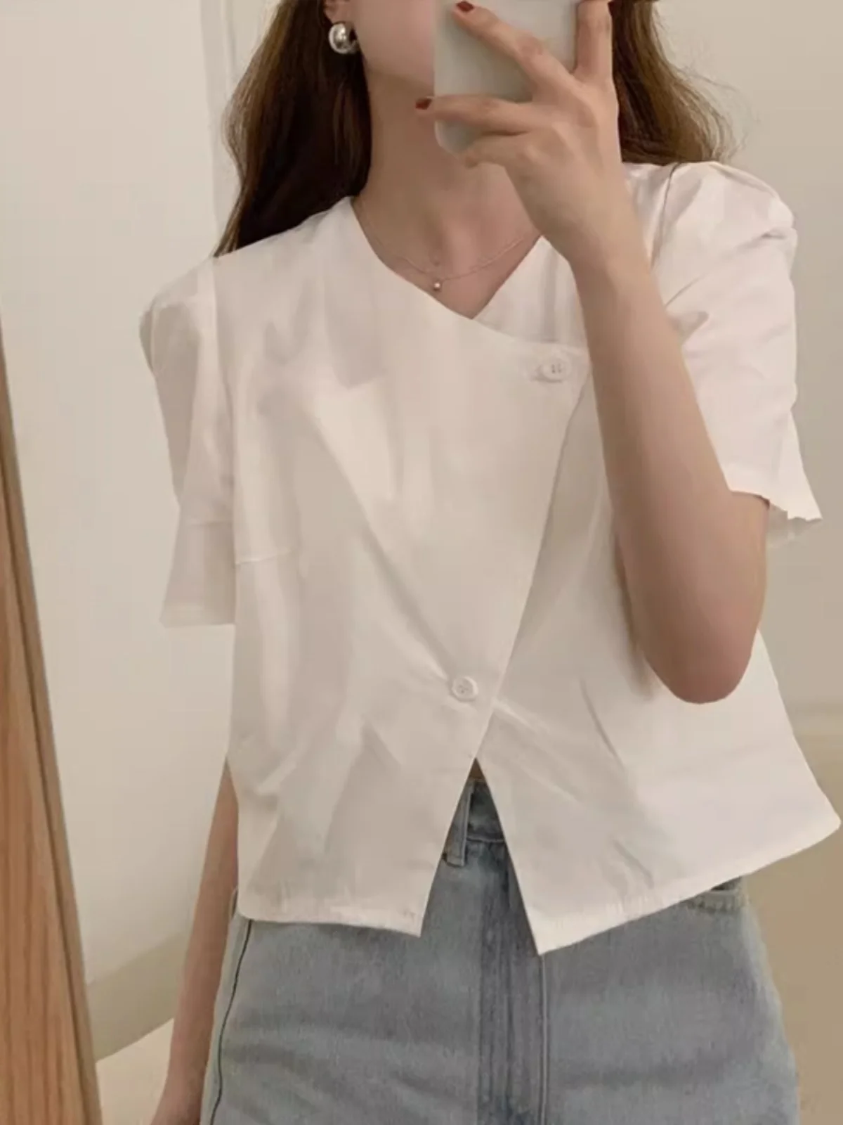 เสื้อสตรีสีขาวทรงหลวมแบบมีระบาย ดีไซน์เก๋ไก๋สำหรับฤดูร้อน คอวีแบบไม่สมมาตร ติดกระดุม ดีไซน์เรียบง่าย เหมาะสำหรับใส่ไปทำงาน สีพื้น