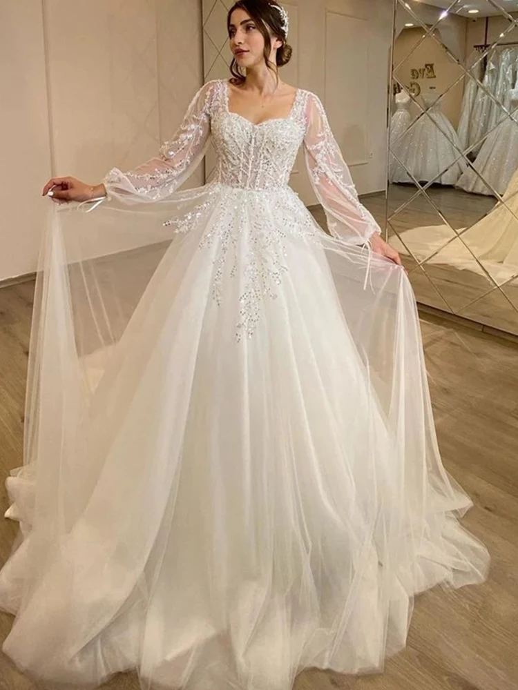 ชุดแต่งงานที่สง่างาม Organza เย็บปักถักร้อยประดับด้วยลูกปัด A-Line Ball Gown สแควร์คอแขนยาวชุดเจ้าสาวปุ่มที่กําหนดเอง