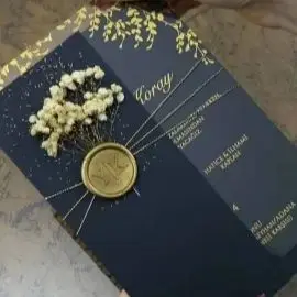 Złota folia na zaproszeniu ślubnym arabskim, niebieska koperta, papier pergaminowy z złotym połyskiem, wiązany sznurek, możliwość personalizacji pieczęci, suszone kwiaty.