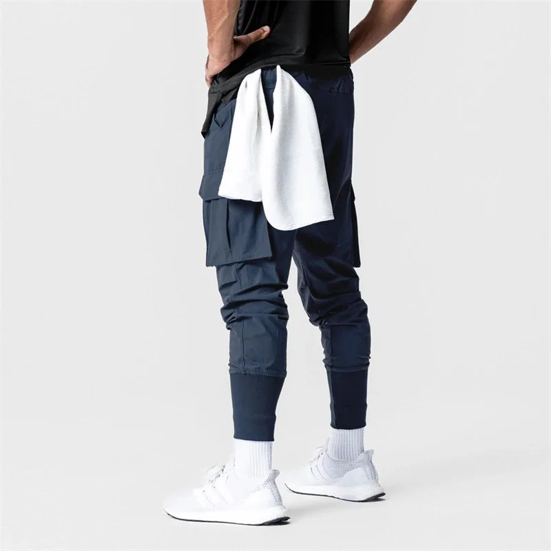 Pantalones deportivos de gimnasio para hombre, ropa de calle para fitness al aire libre, elásticos, con múltiples bolsillos, a la moda, novedad de