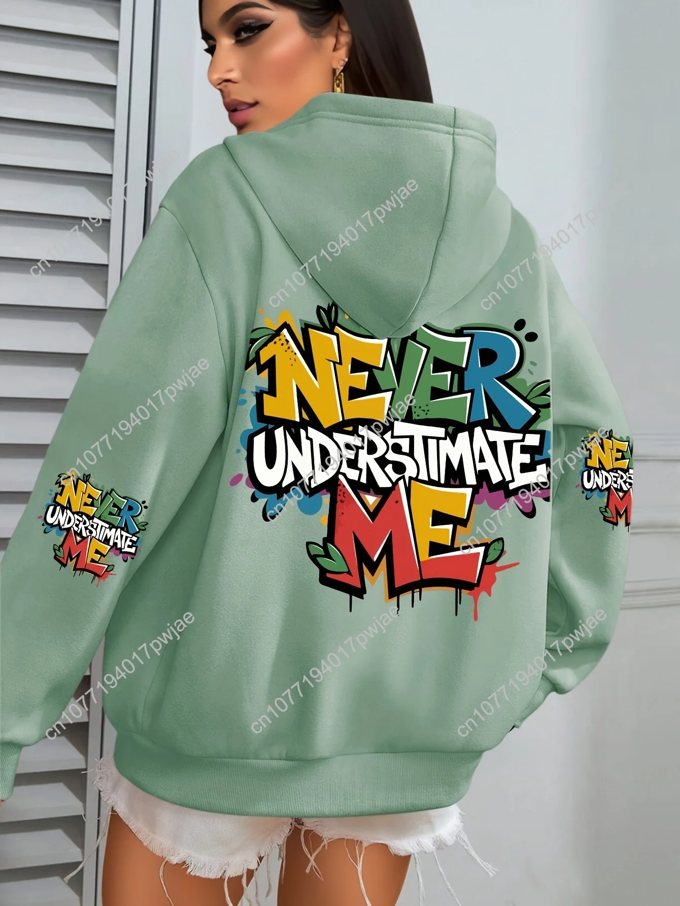 Moletom feminino plus size com estampa grafite hip hop – gráfico "NEVER UNDERESTIMATE ME", verde vibrante com design de respingos coloridos,