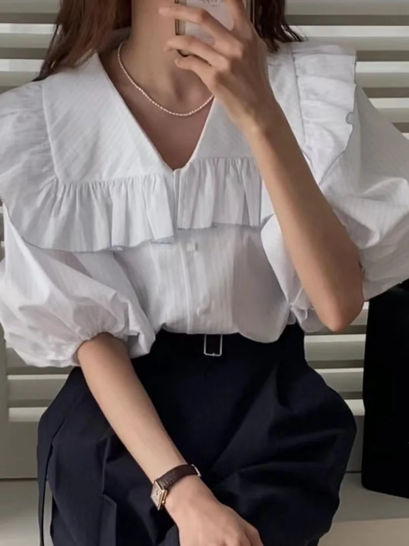 Csa fena e e simples com gola azul marinho, manga bufante com babados e botão único, estilo verão.