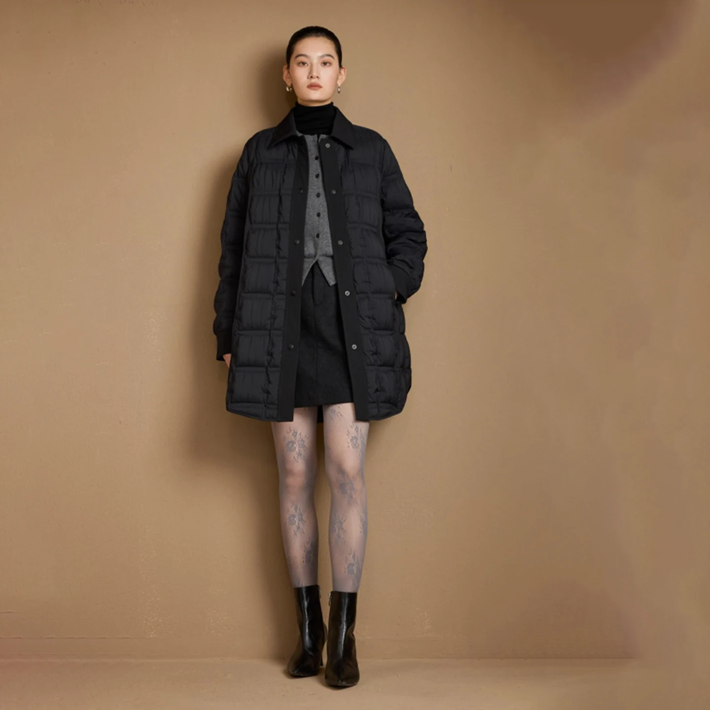 Un piumino da donna di media lunghezza di un marchio internazionale con colletto POLO, con coste corte e sottili per il calore invernale