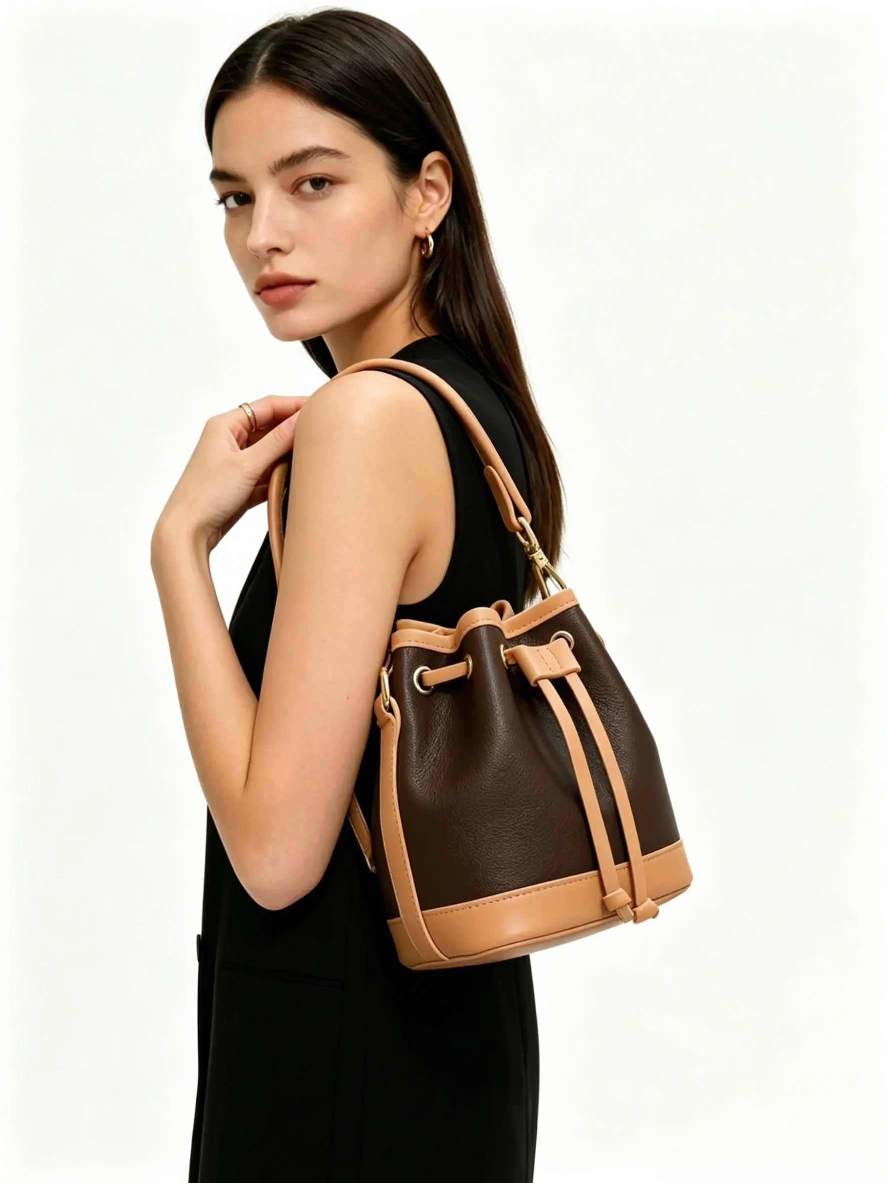 

Two-tone brown and tan leather bucket bag with drawstring closure, gold-tone hardware, and a detachable crossbody strap.