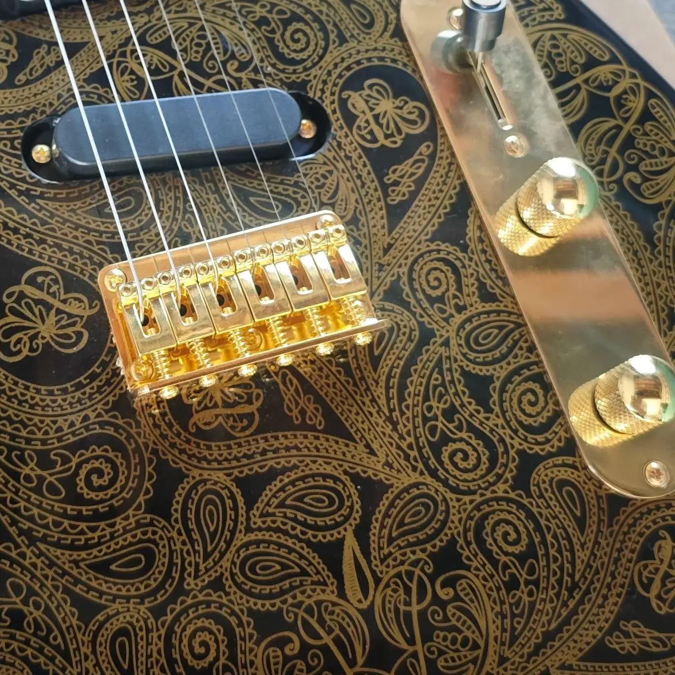 Black six-string electric guitar, gold printed basswood body, maple neck and maple fingerboard with gold hardware.