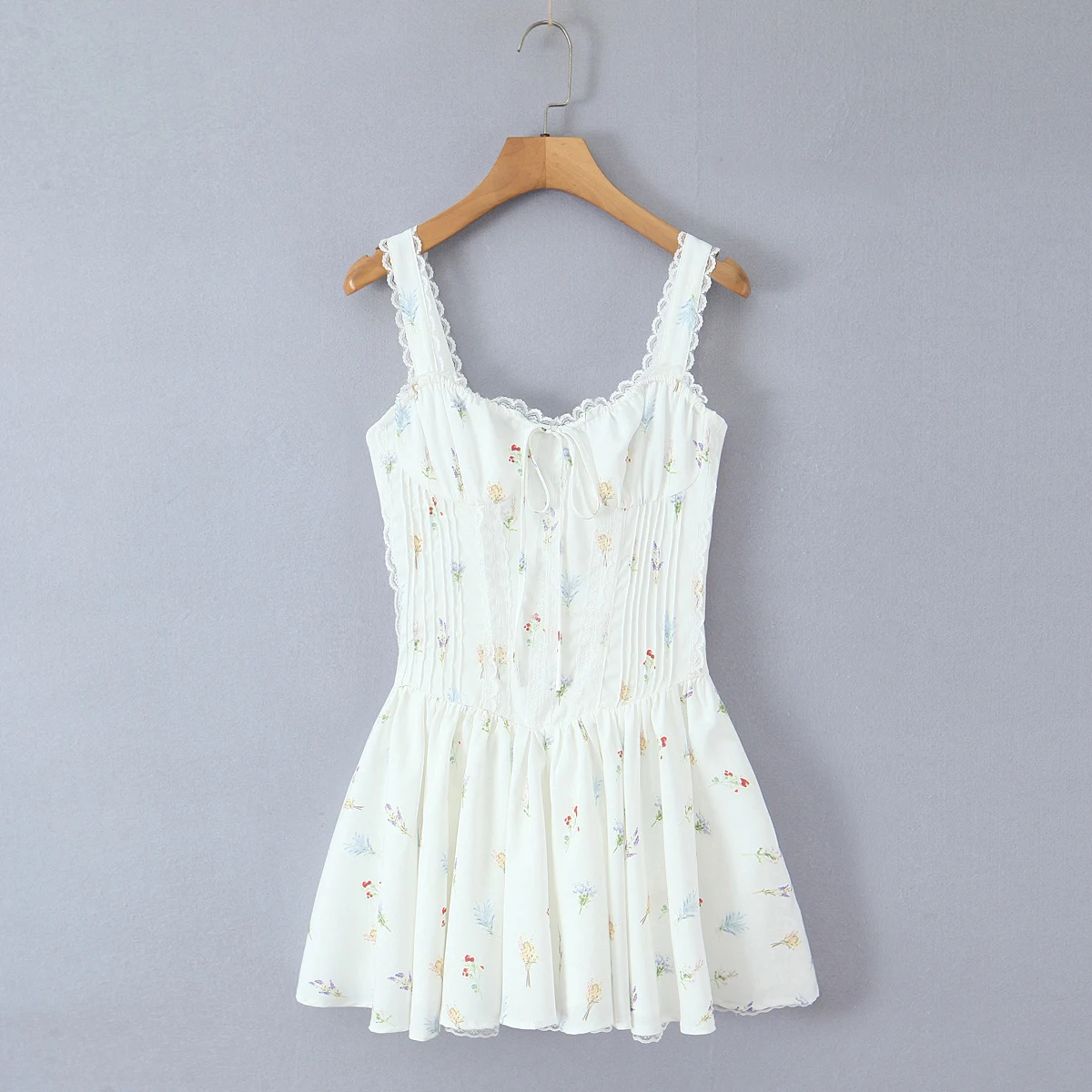 甘い花柄プリントとレースを組み合わせた、胸元にギャザーが入ったミニ丈のスリングドレス。女性用、クロスバックで紐を結ぶ、ローウエストのAラインスイングタンクドレス。