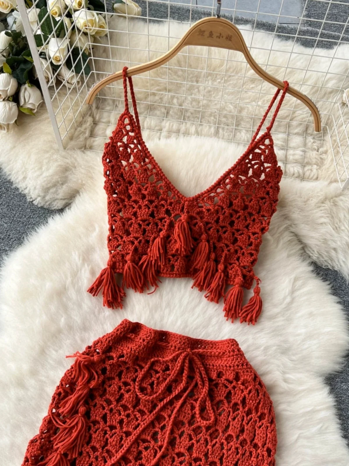 Conjunto de duas peças com top bustiê boêmio vazado com franjas e decote em V e saia curta justa, moda primavera verão fena.