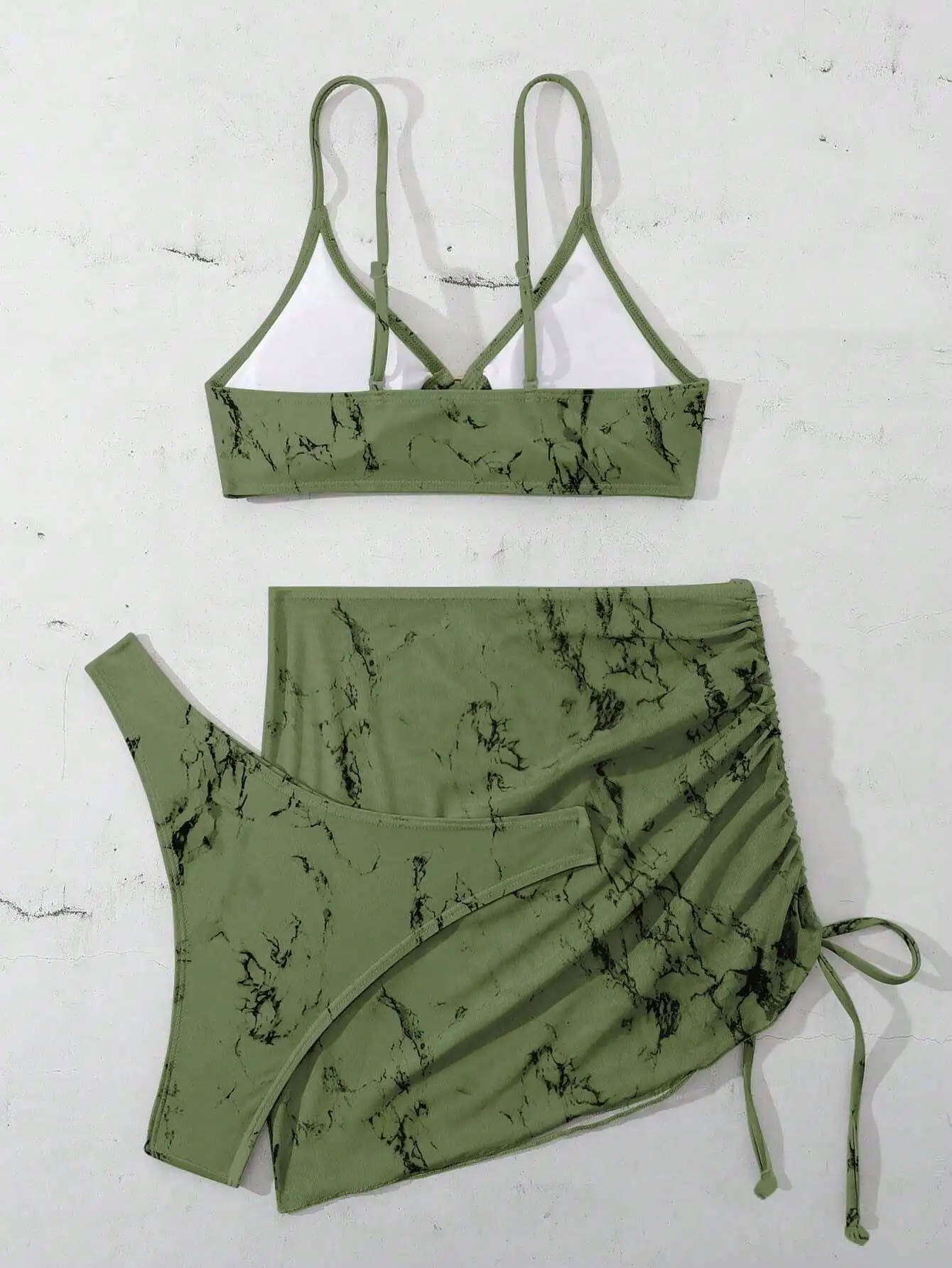 

Комплект из трех предметов: купальник с мраморным узором цвета оливковой зелени, перекрестными бретелями, юбкой-сарафаном с драпировкой и завязками.