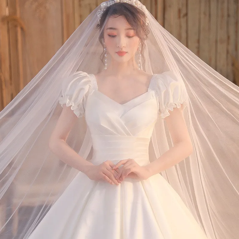 肩が一つになったサテン生地のドレスで、腕を覆う大きなトレーンが付いています。