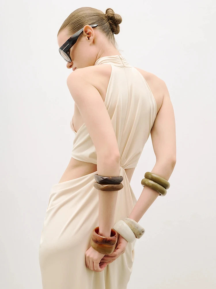 Elegancka, seksowna suknia wieczorowa bez rękawów w kolorze beżowym, z dekoltem typu halter, drapowaniem i wycięciem, idealna na bal maturalny lub przyjęcie koktajlowe.