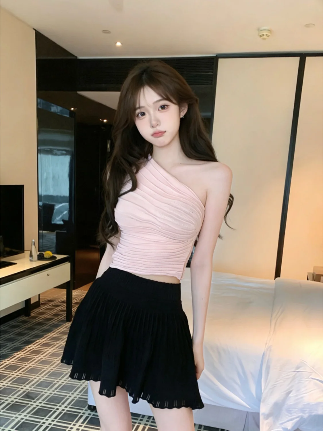 

Комплект из двух предметов: укороченный вязаный топ с одним открытым плечом и плиссированная юбка. Модный женский костюм весна 2026.