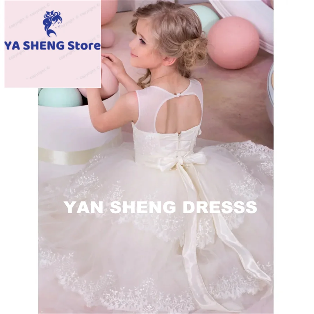 فساتين فتاة الزهور المخصصة من التل العاجي والتطريز بالدانتيل مع حزام فيونكة بدون أكمام لحفلات الزفاف وأعياد الميلاد والتواصل المقدس