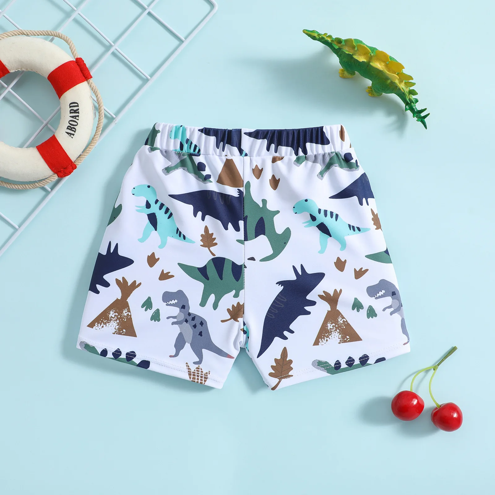 Boys drawstring swim shorts with cartoon dinosaur and plant print on white base suitable for seaside and pool play