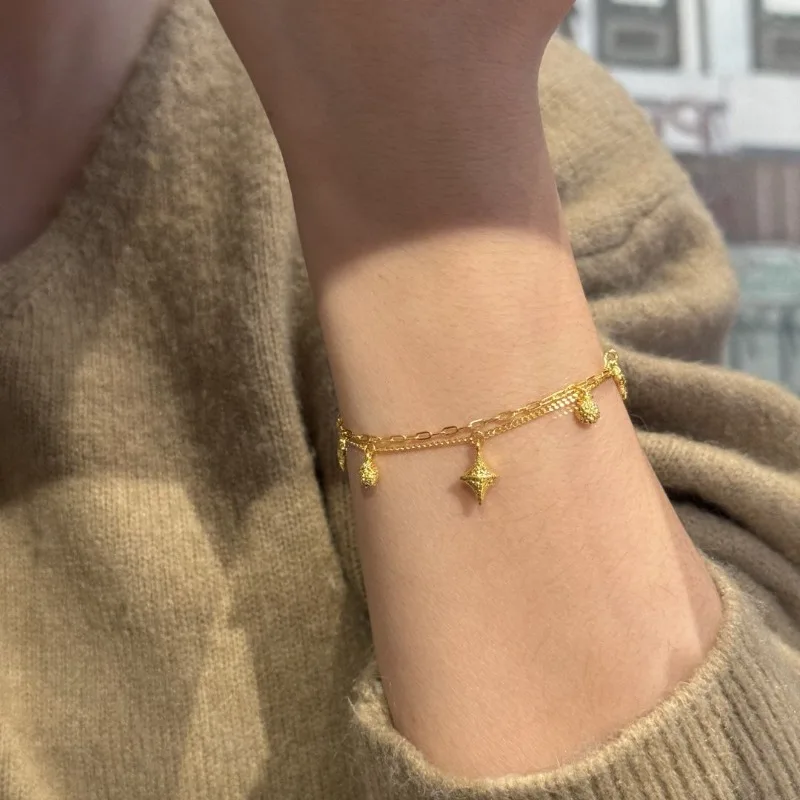 Bransoletka damska w stylu light luxury, złota, z gwiazdą czterokątną, niszowy design, wyrafinowany, podwójny łańcuszek, do noszenia warstwowo, ekskluzywna.