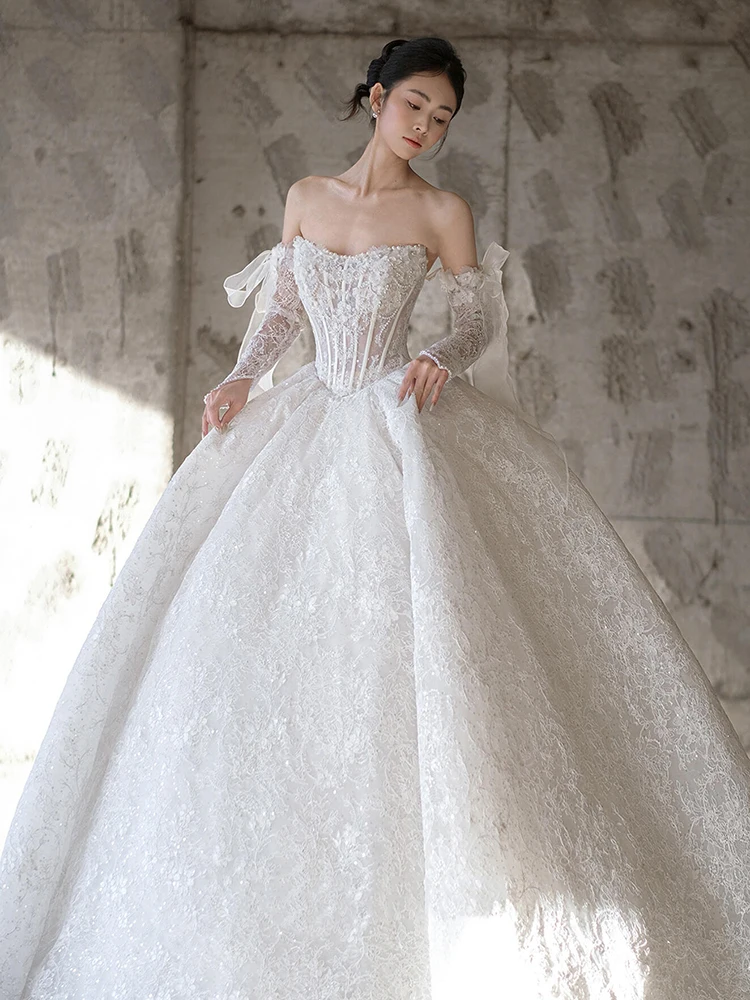 Luxuriöse glitzernde Brautkleider mit langen Ärmeln und trägerlosem Oberteil. Hochzeitskleid für Bräute. Hochwertiges, glänzendes Hochzeitskleid nach Maß