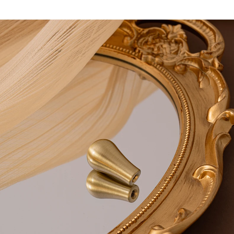 Two teardrop brass knobs shown on a mirror