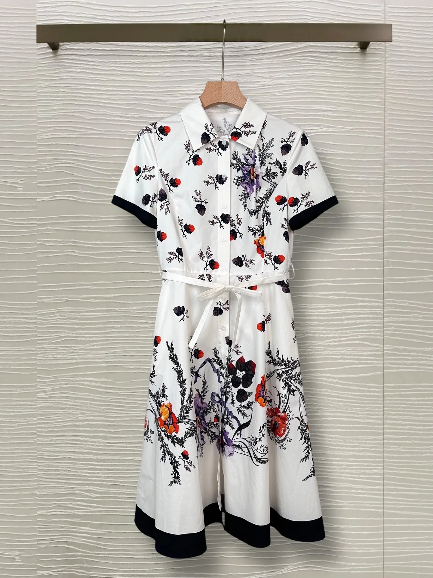 White background retro floral print shirt dress with black border short sleeved shirt and waist cinched mid length skirt