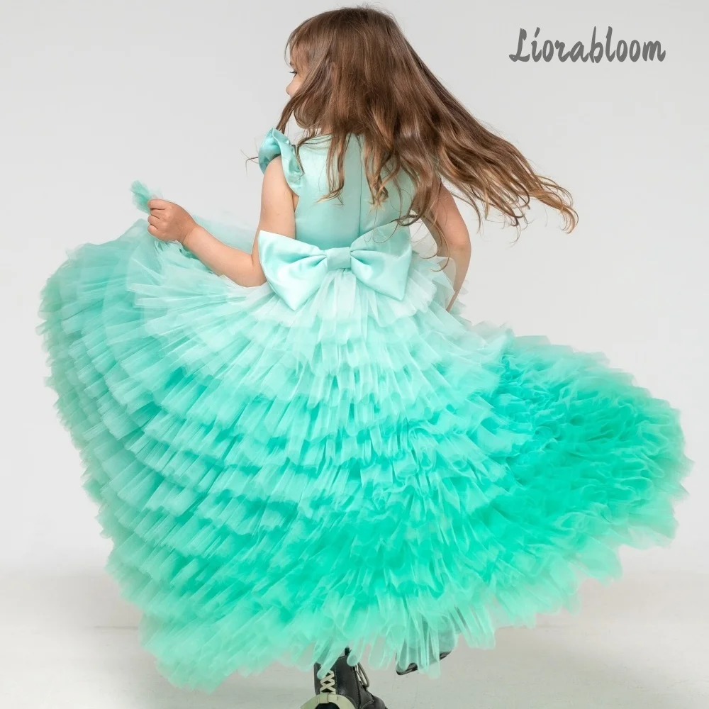 Abito da bambina verde smeraldo con gonna in tulle a balze e maniche con fiocco, ideale per spettacoli, matrimoni e damigelle.