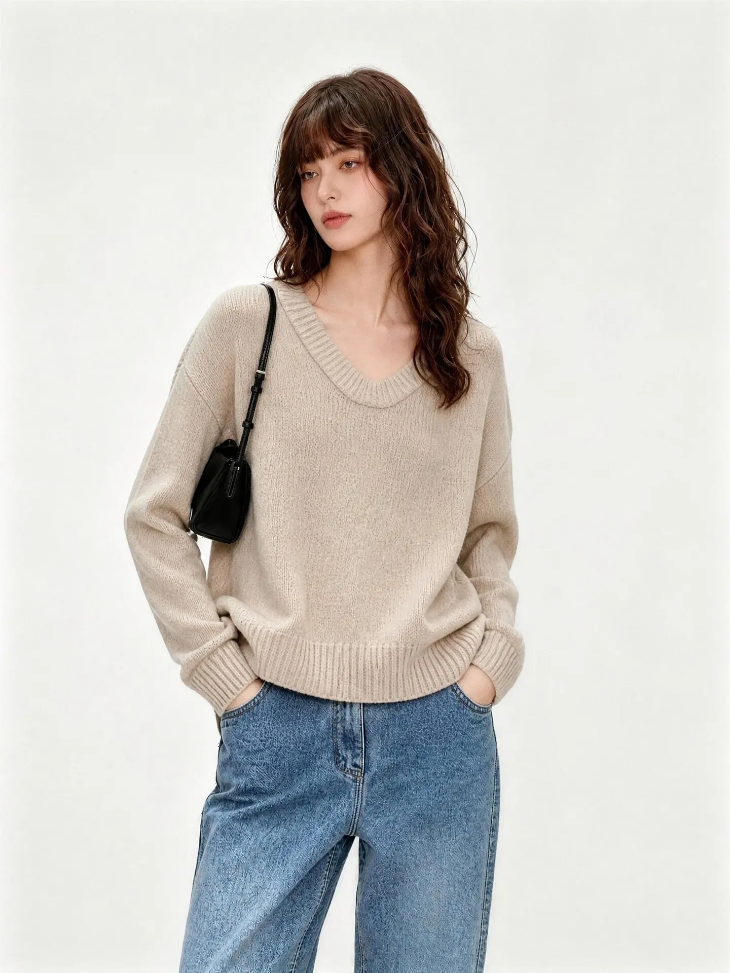 A beige pullover cashmere sweater with a high sense of intelligence is worn with a bottoming coat inside the wind.