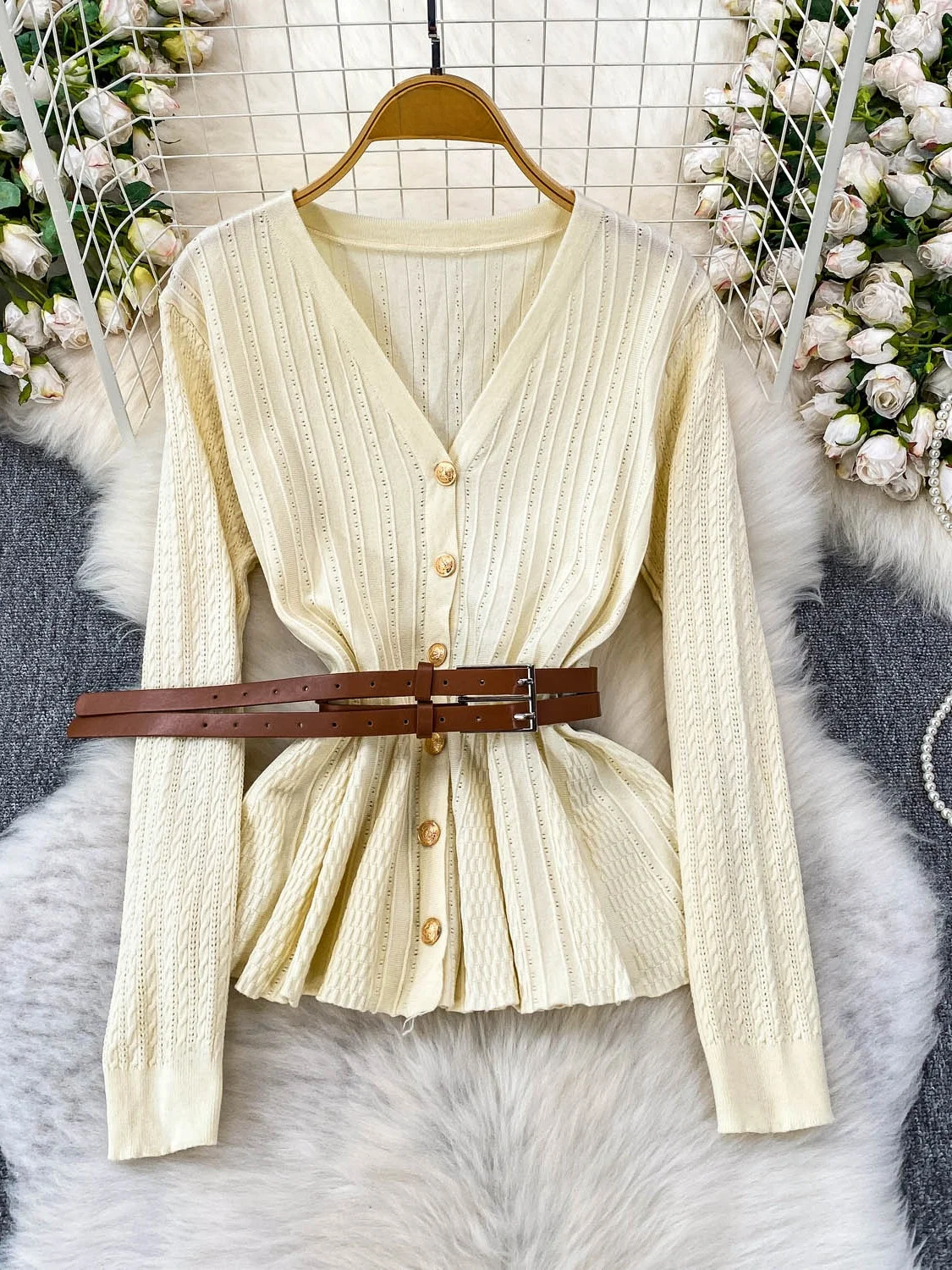 Niebieska dzianinowa bluzka z dekoltem w serek, długim rękawem, ażurowym wzorem, damska, jesienna, elegancka, z paskiem w talii, metalowa, niebieska, delikatny wiatr.