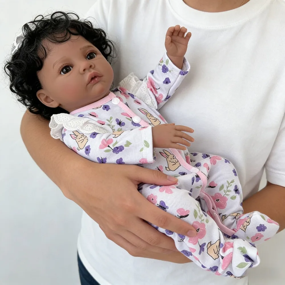 دمية طفلة رضيعة من الفينيل بطول 18 بوصة (45 سم) تشبه الطفل الحقيقي، تدعى ميدو، ببشرة داكنة، تشبه الفتيات الأمريكيات من أصل أفريقي، بشعر أسود مجعد.